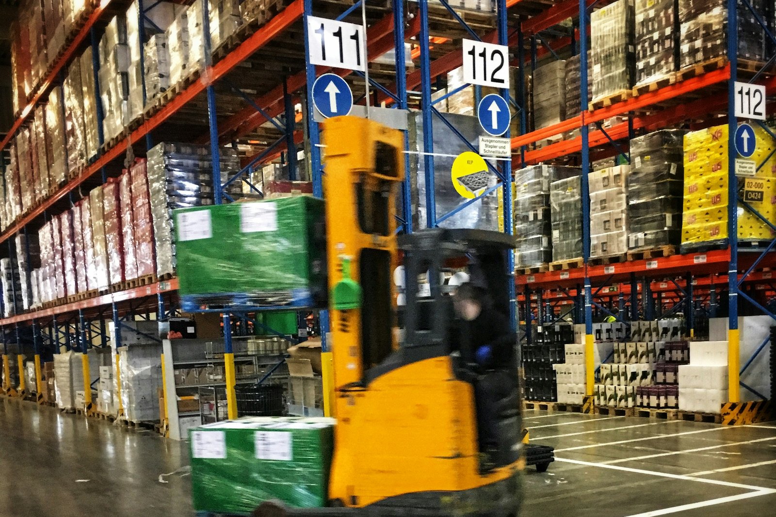 Xe nâng chạy giữa hai dãy pallet trong kho